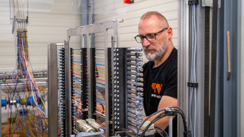 P&V Panels technician working with a Komax wire processing machine and colour-coded electrical wiring.
