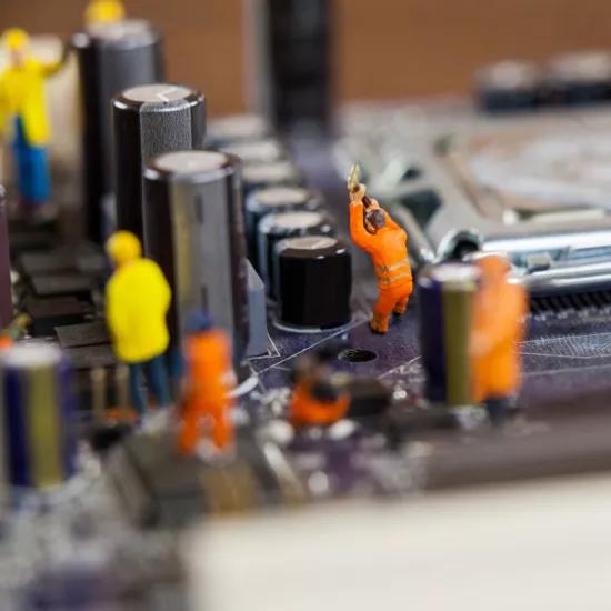 Miniatuurpopjes van remanufacturing werkmannen op realsize moederbord
