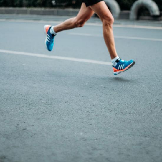 Runner with bare legs and clear blue running shoes running on asfalt road illustrating motion analysis of foot plantar pressure in running exercises