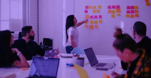People in a brainstorm, looking at post-its on a wall.