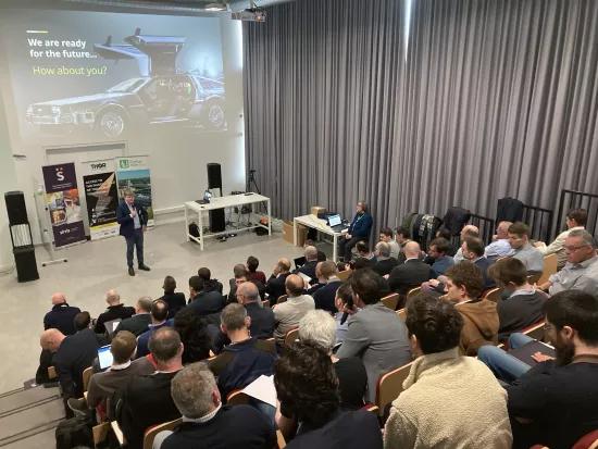 Man standing in front of an audience that is listening to his talk at a seminar. 