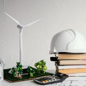 Scale model of wind turbine surrounded by books safety helmet and calculator