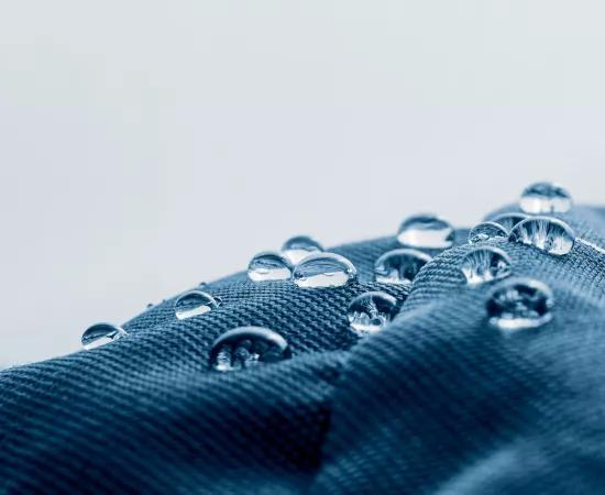 Close-up of water droplets on a hydrophobic and oleophobic textile surface, illustrating the goal of the BIOSUPHYOL industrial research project on bio-based and PFAS-free coatings.